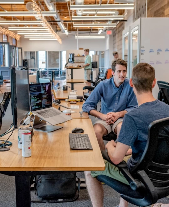 two-men-sitting-on-chair-beside-tables
